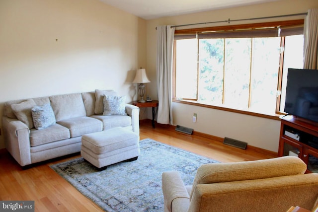 living area with baseboards and wood finished floors