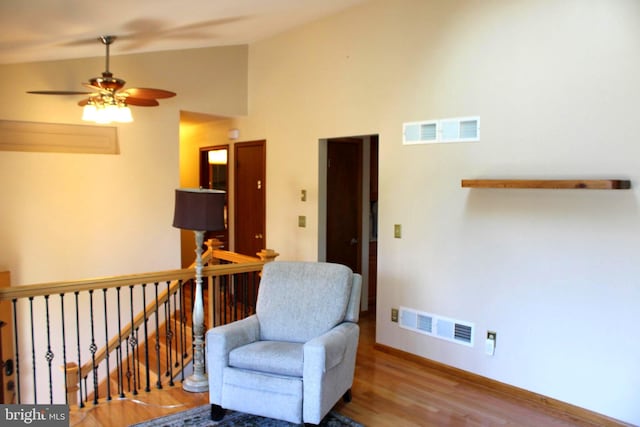 living area featuring visible vents, an upstairs landing, baseboards, and wood finished floors