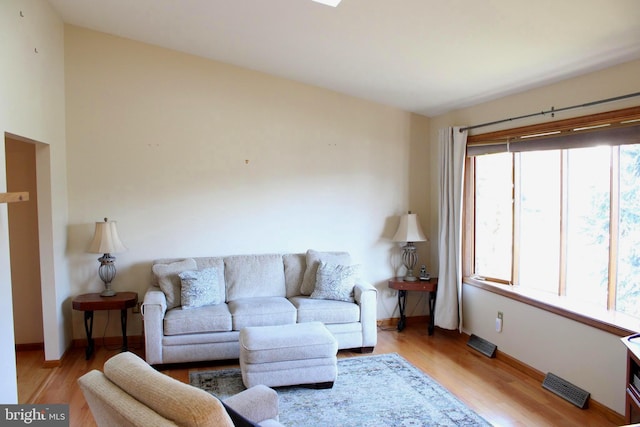 living room featuring visible vents, light wood-type flooring, and baseboards