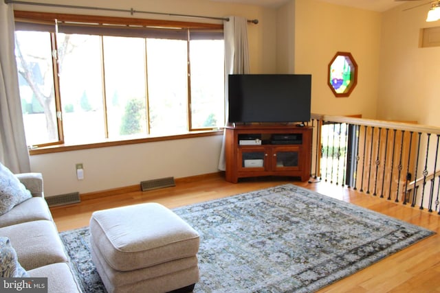 living room with wood finished floors, visible vents, and baseboards