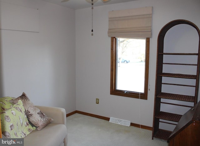 living area with visible vents, light colored carpet, and baseboards