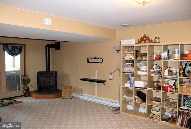 interior space featuring baseboard heating, a wood stove, and carpet