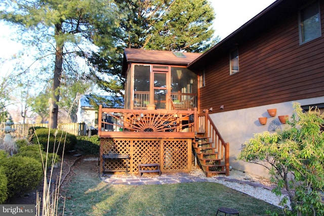 exterior space featuring a lawn, a deck, stairs, and a sunroom