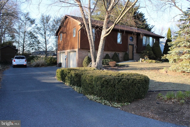 split foyer home featuring a garage, brick siding, and driveway