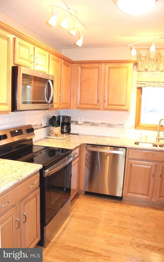 kitchen featuring a sink, tasteful backsplash, appliances with stainless steel finishes, and light wood finished floors