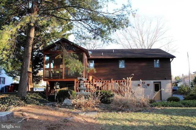 rear view of house with stucco siding and a sunroom