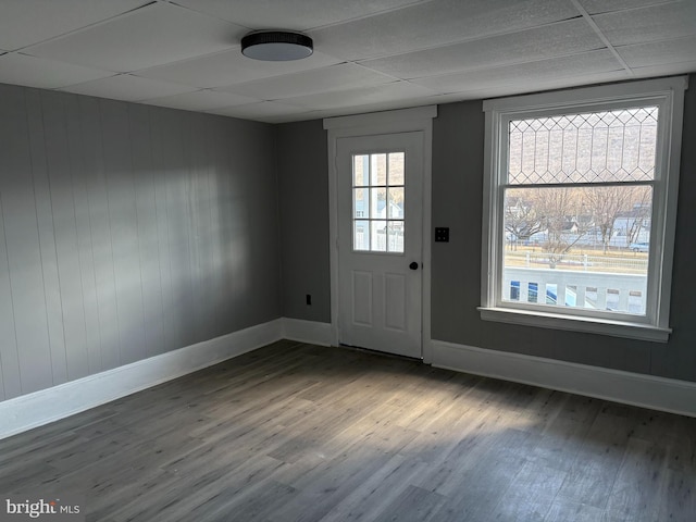 doorway to outside featuring a drop ceiling, wood finished floors, and baseboards