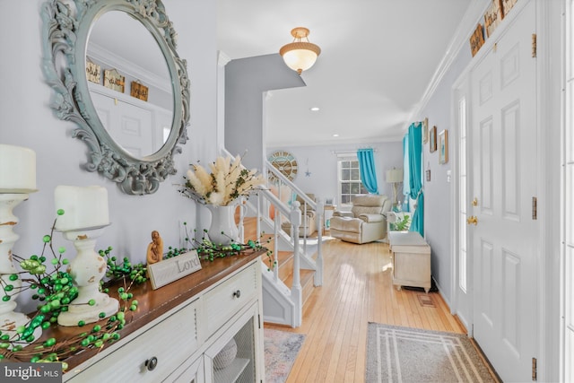 foyer with stairway, crown molding, and light wood-style floors