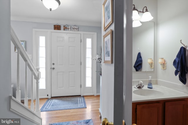 foyer featuring stairs, light wood-type flooring, plenty of natural light, and crown molding