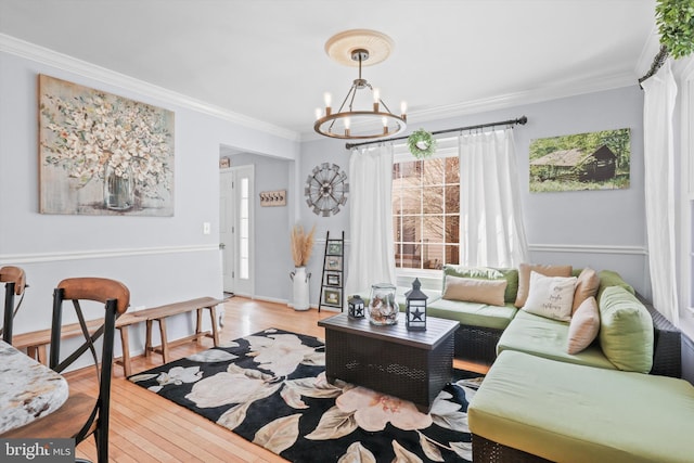 living room featuring baseboards, wood-type flooring, an inviting chandelier, and ornamental molding