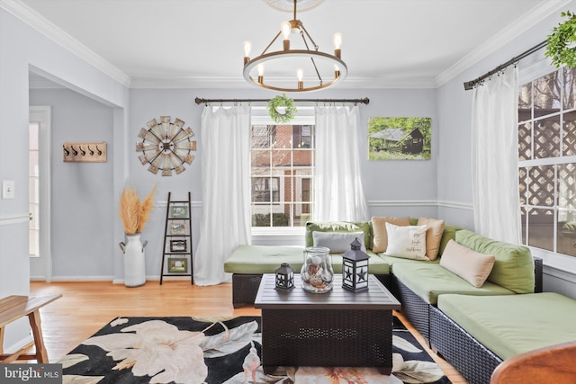 living room with crown molding, a notable chandelier, wood finished floors, and baseboards