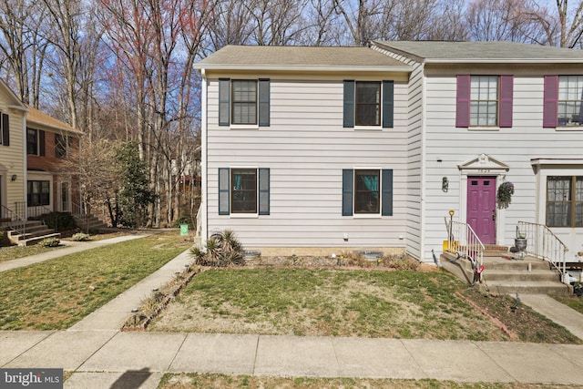 view of property with a front lawn and roof with shingles