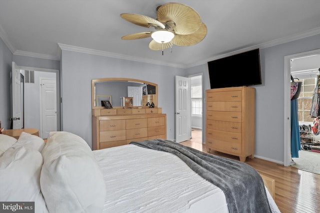 bedroom with light wood-style floors, a spacious closet, and crown molding