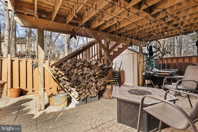 view of patio / terrace featuring a fire pit, stairs, a fenced backyard, an outbuilding, and a storage unit