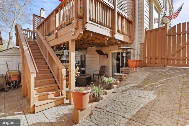 view of patio / terrace with a storage unit, a gate, fence, an outdoor structure, and stairs