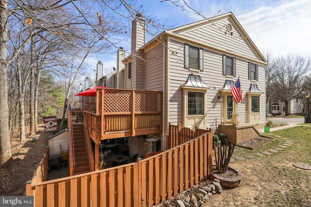 rear view of property with a deck, a chimney, and fence