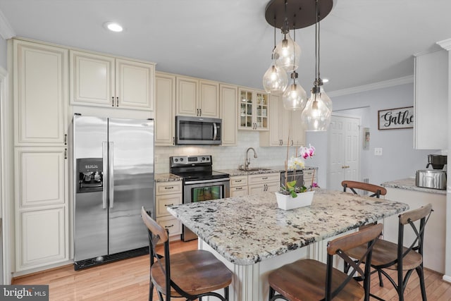 kitchen with a sink, stainless steel appliances, a kitchen breakfast bar, and cream cabinets