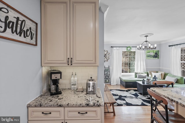 kitchen with cream cabinetry, light stone counters, tasteful backsplash, wood finished floors, and crown molding