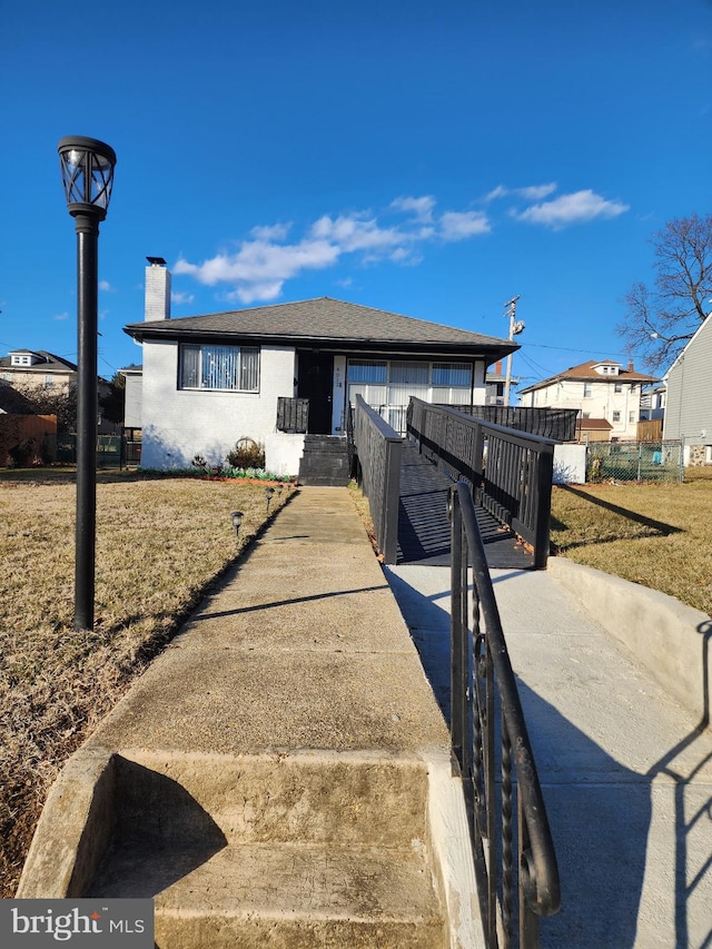 view of front of home with fence, roof with shingles, and a chimney