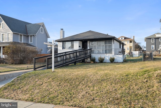 view of front facade featuring a chimney, a front yard, and fence