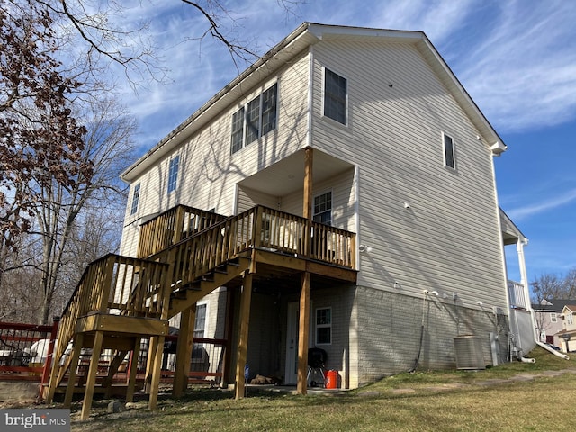 back of property featuring a deck, stairway, a lawn, and brick siding