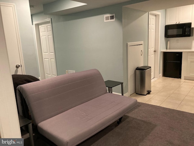 living area with light tile patterned floors, light colored carpet, and visible vents