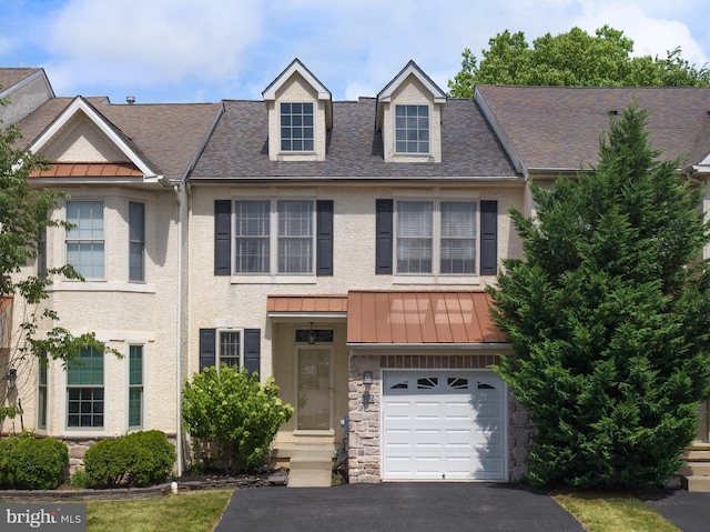 view of property with metal roof, a garage, stone siding, driveway, and a standing seam roof