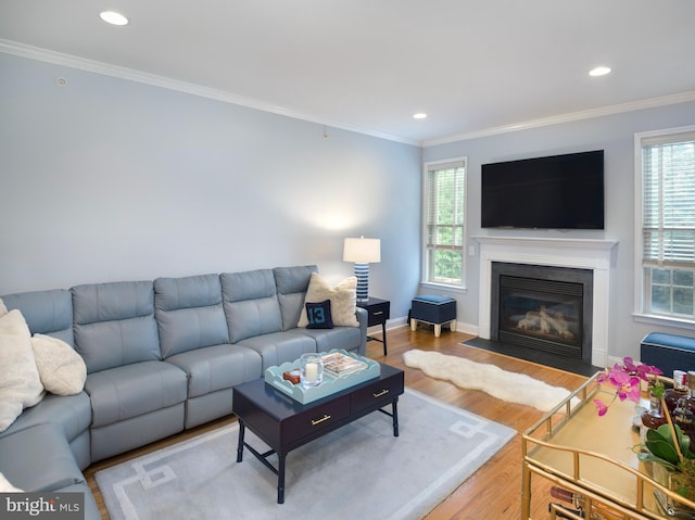 living room with a fireplace with flush hearth, wood finished floors, recessed lighting, crown molding, and baseboards