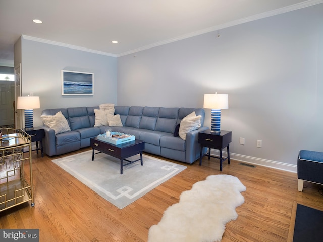 living room with crown molding, wood finished floors, baseboards, and visible vents