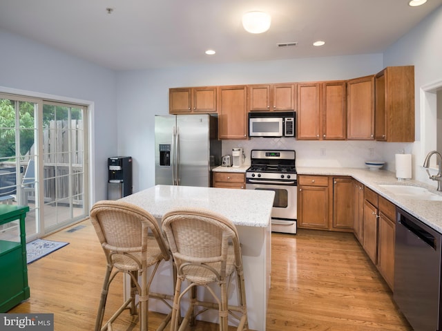 kitchen featuring tasteful backsplash, light wood-type flooring, brown cabinets, stainless steel appliances, and a sink