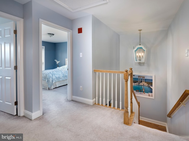 hall featuring an upstairs landing, baseboards, and carpet floors