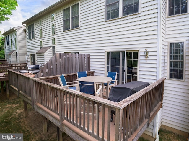 wooden terrace with a grill and outdoor dining area