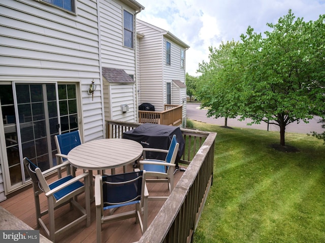 deck featuring outdoor dining space and a lawn