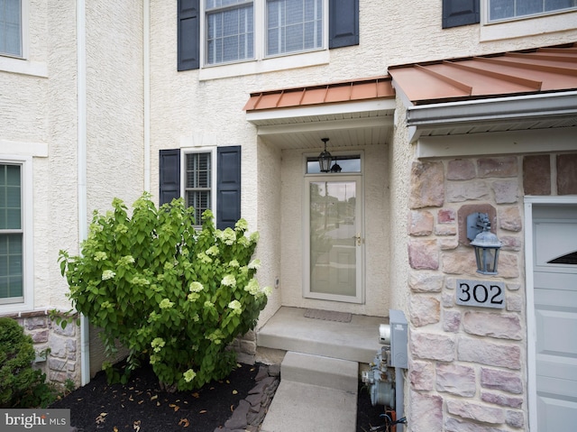 view of exterior entry featuring stucco siding and a garage