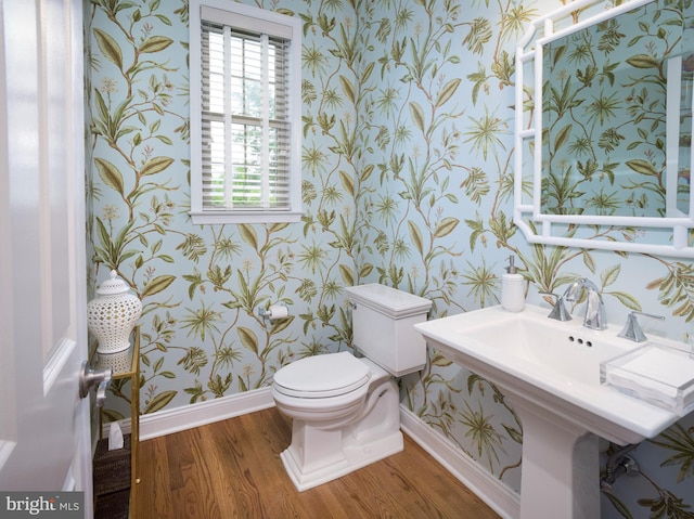 half bath featuring baseboards, toilet, wood finished floors, and wallpapered walls