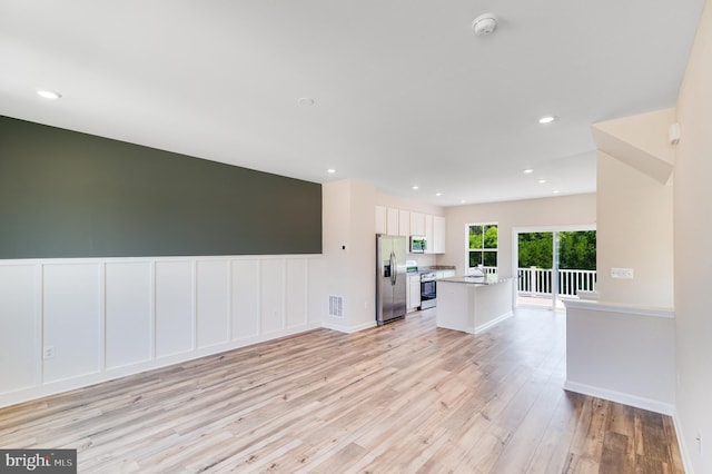 kitchen featuring visible vents, white cabinets, light wood-style flooring, open floor plan, and stainless steel appliances