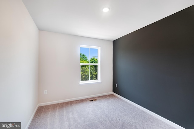 unfurnished room with carpet, visible vents, and baseboards