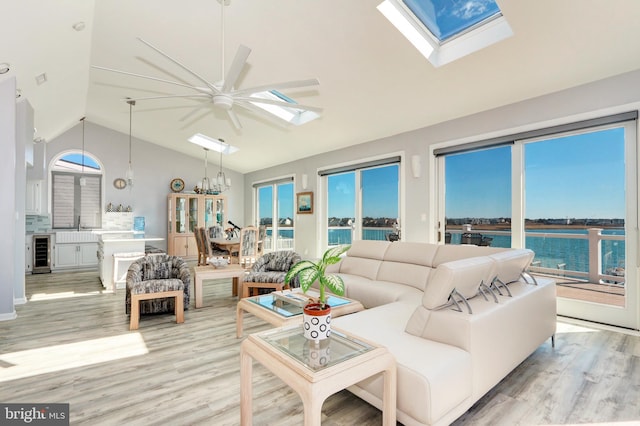 living room with wine cooler, high vaulted ceiling, a skylight, and light wood finished floors