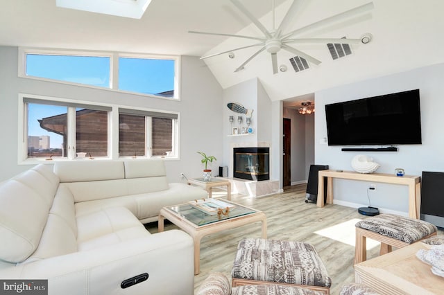 living room featuring a glass covered fireplace, wood finished floors, visible vents, and a healthy amount of sunlight