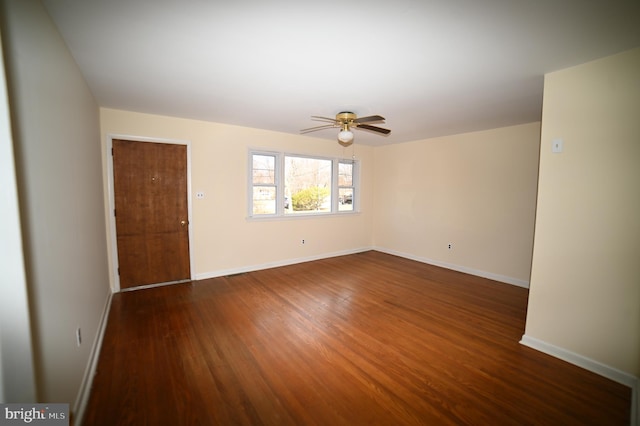 spare room featuring dark wood-style floors, baseboards, and a ceiling fan