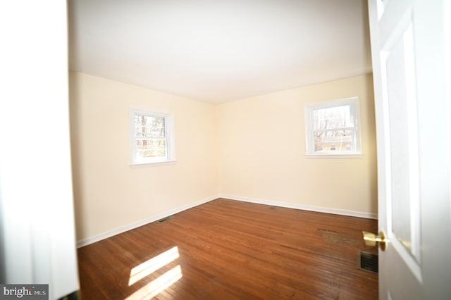 spare room with visible vents, baseboards, and wood finished floors