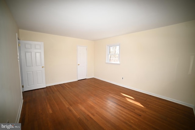 spare room featuring dark wood-type flooring and baseboards