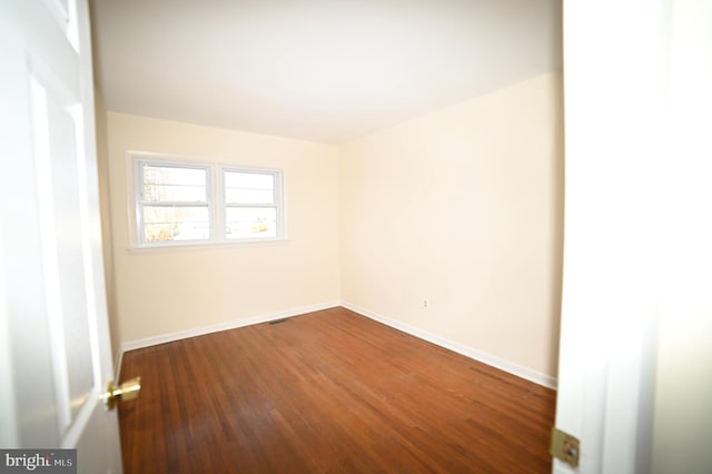 empty room featuring visible vents, baseboards, and dark wood-style floors