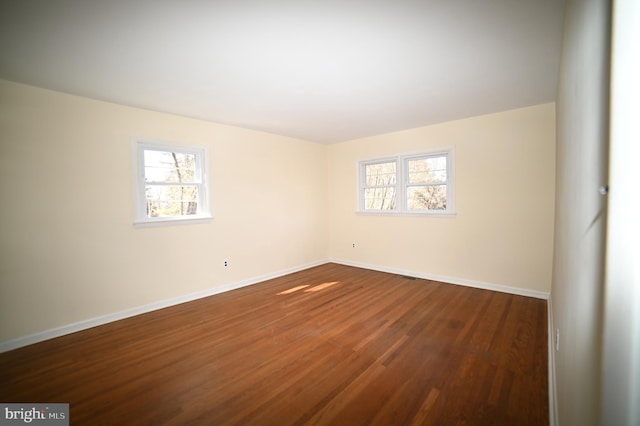 spare room featuring baseboards and dark wood-style flooring