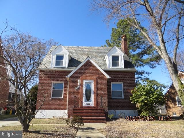 new england style home with brick siding and a chimney