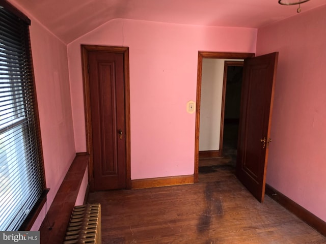 interior space with radiator heating unit, baseboards, vaulted ceiling, and wood finished floors