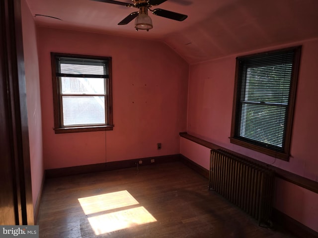 additional living space with wood finished floors, a ceiling fan, baseboards, vaulted ceiling, and radiator heating unit