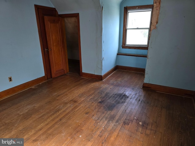 spare room featuring wood-type flooring and baseboards