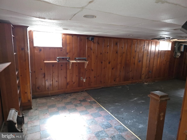 below grade area with wooden walls, a healthy amount of sunlight, and tile patterned floors