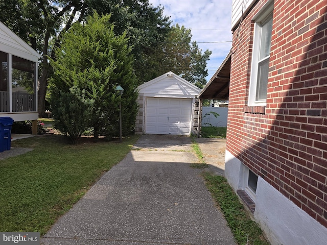 view of home's exterior featuring driveway, a detached garage, a yard, an outdoor structure, and brick siding